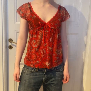Röd mönstrad meshtopp - Jättesöt röd mönstrad topp med rosett under bysten❤️Fin lite djupare ringning. Helt perfekt skick. Passar XS/S. Skriv vid funderingar och kolla in mina andra annonser🪩