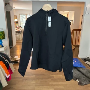 ALTA LS HOODIE J.Lindeberg - Hoodie som fungerar som midlayer för herr i storlek M från J.Lindeberg. Nypris 2000 kr🥰oanvänd med prislapp kvar! Superskönt material av polyamid och elastan som j.lindeberg gör allra bäst
