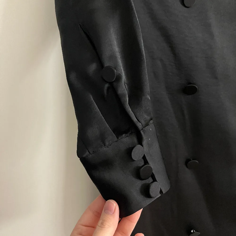 Svart elegant skjortklänning från Stockholm LM.  knälång. Har knappar och skärp samt fina detaljer. Använd 1 gång - som ny . Klänningar.