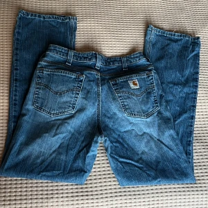 Carhartt Blå Jeans - Den perfekta jeansen! 😍Carhartt vintage blå jeans i en bootcut/flare modell, low waisted/regular midja. I använt skick men inga skador på jeansen. Ungefär 28/30 i storlek, så kortare i benen men något bredare i höften ☺️ Säljer pga för stora för mig. 