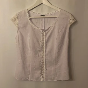 Vit topp - Vit topp med fina detaljer. Dragkedja i ryggen. Märke: Satin. Storlek: 38