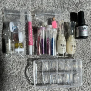 Nageltillbehör - Flera nageltillbehör som genomskinliga tippar, glitter, stenar, nail-strengthener, ett vitt UV gellack, nagelbandsolja. Det mesta använda några gånger. Vid intresse/fler bilder skriv! Köps tillsammans, vid separata köp skriv först 🫶🏻 100 kr för allt!!