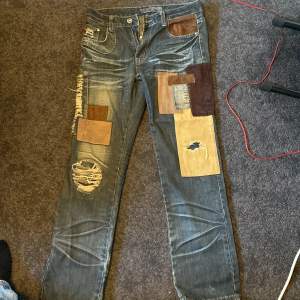 Helt unika jeans som jag har ärvt. Lapparna är påsydda efter jeansen var köpta. Vet inte själv hur gamla de är, men helt klart de coolaste jeansen jag har ägt. Midjan är i storlek 34, längd står ej men skulle uppskatta dem som 33/34.