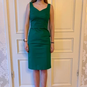 Grön klänning, Emmy design  - Jättefin grön klänning i skönt material. Storlek 38.  Modellen på bilden är 173 cm och har storlek 38 i de flesta andra kläder. Aldrig använd. Vi har lagt ner vår klänningsbutik och säljer ut. Ny pris är 2000-3000kr