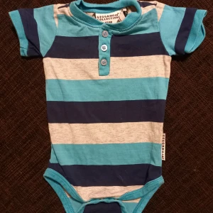 Kortärmad body strl. 62/68 - Kortärmad body med ränder i storlek 62 från Geggamoja. I fint begagnat skick, inga hål eller fläckar.   Tvättad i parfymfritt tvättmedel och utan sköljmedel.