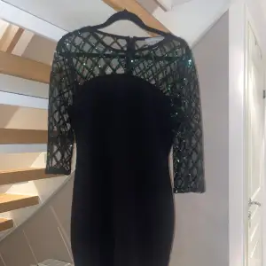 Detta är en svart cocktail klänning med gröna paljetter på överdelen. Köpt från Zalando och använd en gång. 
