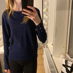 Stickad tröja - Mörkblå stickad tröja från Lindex med guldiga knappar på sidorna. Inga defekter. Originalpris: 300