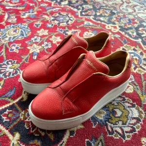 Russel&Bromley sneakers - Sneakers i snygg klarröd färg från Russel&Bromley. Inköpta i London för omkring 2.000kr. Något smutsig sula men annars i relativt fint skick. Storlek 38. Upplevs små i storleken.