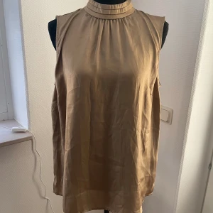 Guldig topp strl L - Guldig topp i strl L Med halv polokrage Använd 2ggr Så fint skick