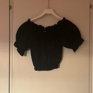 Svart topp - En kort svart topp med ballongärmar och tunt material. Är i gott skick.