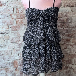 Blus - Blus med volanger och blommor. Extra tyg vid bysten som knyts🌸🖤 står inte storlek men sitter som en S