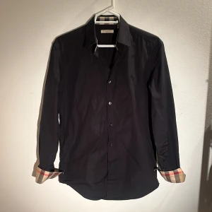 Burberry skjorta  -  Säljer min burberry skjorta som är i näst intill perfekt skick, finns några mindre flaws på ärmarna! Nypris på över 4999kr, men jag säljer för 899kr! Hör av er vid frågor, funderingar eller efterfrågan av fler bilder!
