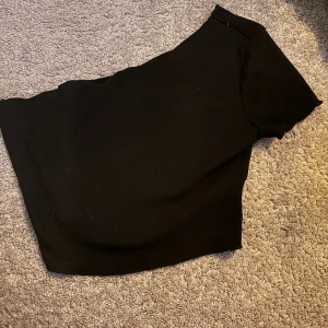 Svart topp - En svart topp med en Axel, den sitter sne över.