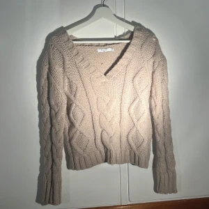 Stickad tröja  - Stickad tröja med v-rigning i en brun/beige färg 