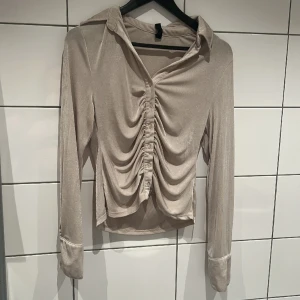 Tröja  - Använd 1 gång. Tunnt fint material. Knappar längst ner på armarna. 