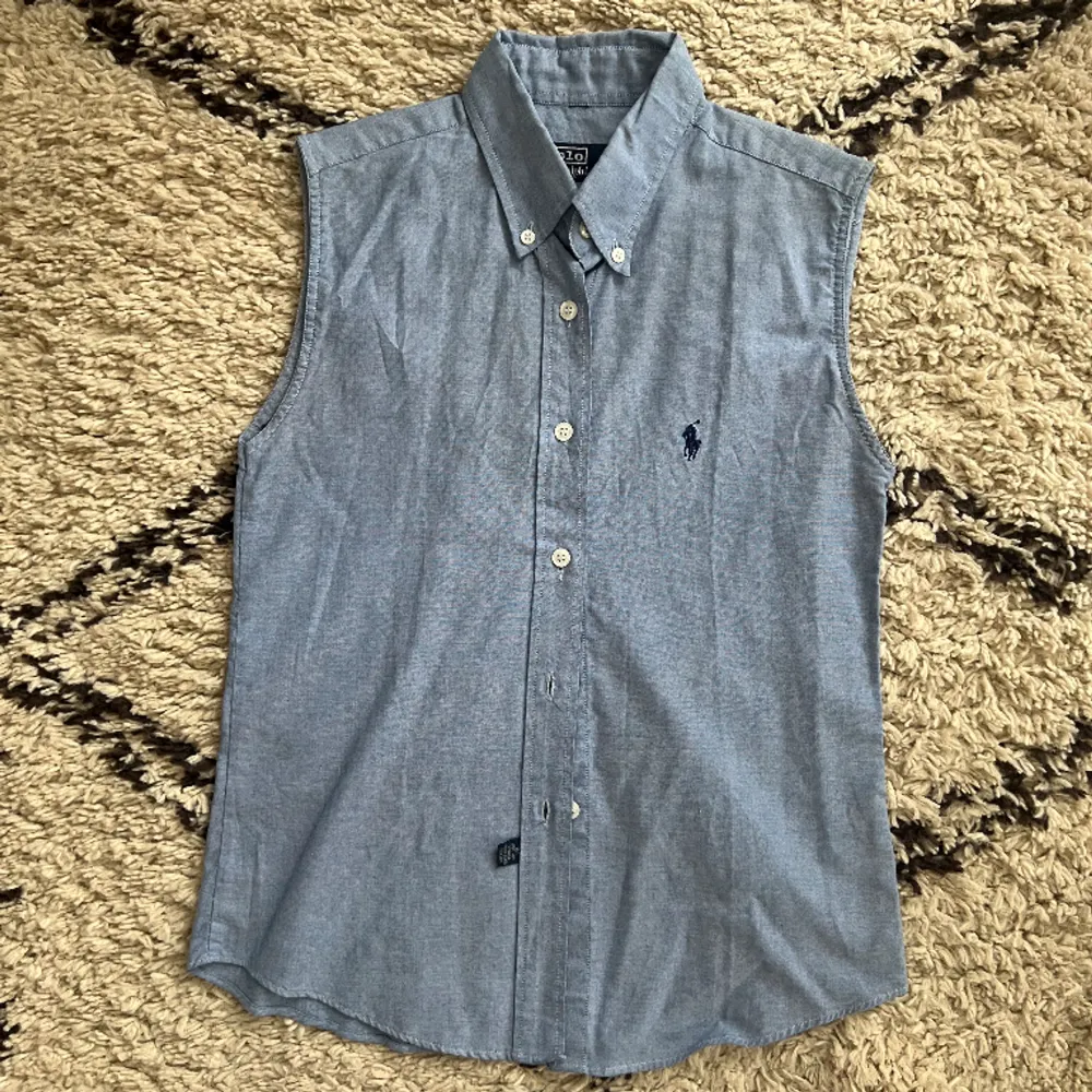 Ärmlös skjorta i ljusblå från Ralph Lauren🌹 Perfekt att ha u der en stickad tröja😍 Sparaamt använd! . Skjortor.
