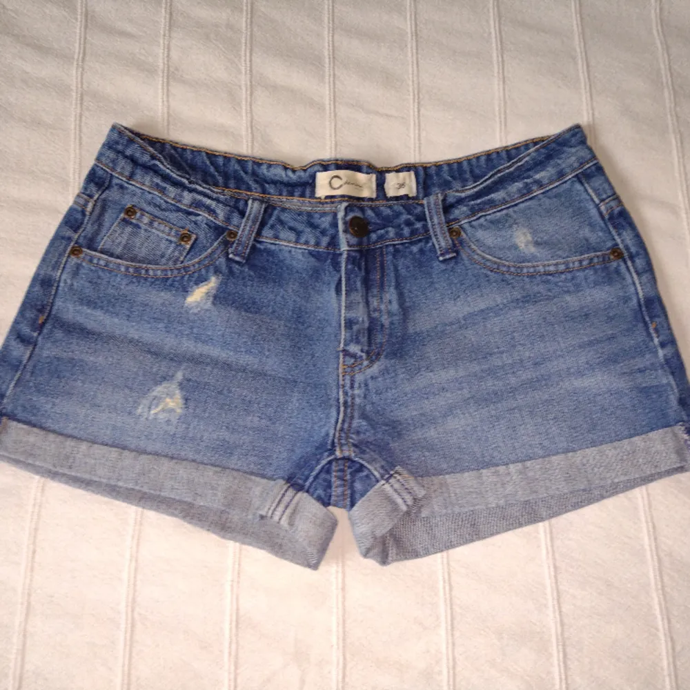 Blå korta jeansshorts från Cubus i 100% bomull. Sparsamt använda och i fint skick. Snygga slitna detaljer och låg midja. Storlek 36.. Shorts.