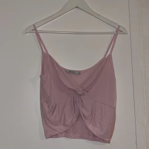 Rosa topp - En söt tunn rosa topp från NA-KD. Men en fin detalj i mitten, går att justera tajtare och lösare. Är i storlek: XS men sitter som XS/S. Aldrig använt och är bra skick. Frakt ingår med 29kr. 