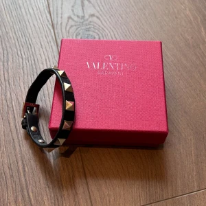 Valentino armband  - Svart Valentino armband med silvriga studs i nyskick, kommer med box, dustbag, extra nitar och äkthetsbevis. Nypris 3100 mitt pris 1300kr. Över 70 nöjda kundrecensioner finns, bara att skriva vid frågor eller funderingar!
