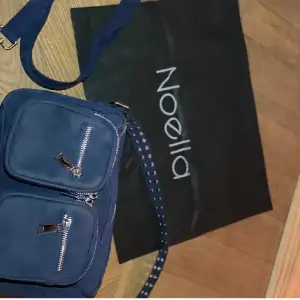 Säljer min mörkblå noella väska i mocka, fint skick men inte nyskick✨Följer med en extra axelrem och dustbag. Höjd: 18 cm, Djup: 10, bred 28 cm. ❤️❤️