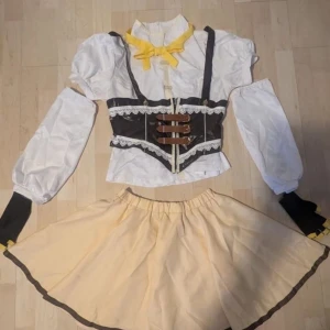 Mami Tomoe Puella Magi Madoka Magica cosplay - In good condition except for the feathers on the hat. Was bought for 1000kr originally. The  lower arm sleeves have been sewn out because they were too small but can be fixed and barely is noticeable. Includes heavily styled wig hence the price.