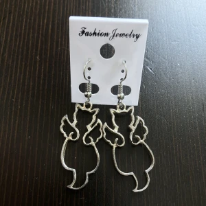 Silverfärgade örhängen med katter, ängel, katt, djur, dangly, hängande - Silverfärgade örhängen med katter, finns missfärgningar. Längd: 5,5 cm.