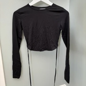 Svart topp med öppen rygg  - Svart topp med öppen rygg från Bershka! Endast använd en gång, fint skick! 