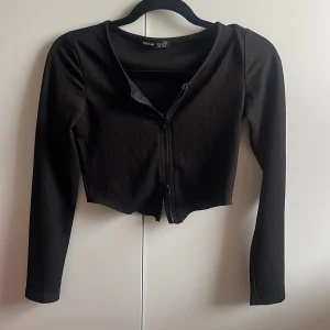 Svart tröja - Svart tröja med dragkedja som man kan justera själv. Använd 1 gång. Mjuk och bra skick, ribbad. 