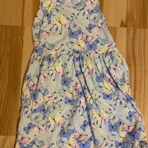 Klänning fjärilsmönster - Strl 134/140. Säljes i begagnat skick. Kolla gärna in mina andra annonser för samfrakt! Jag är väldigt mån om mina köpare. Skulle du vara missnöjd med ditt köp så ta gärna kontakt med mig innan dåligt omdöme, så har jag en chans att rätta till det.