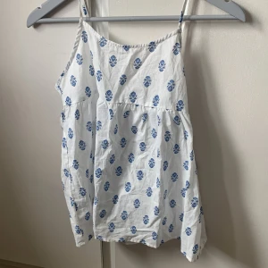 Vitt Linne med blåa mönster - Jätte fint linne i mycket gott skick. Linnet har en rosett på baksidan.