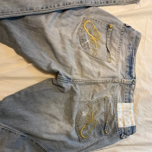 Bootcut jeans - Superlågmidjade bootcut jeans med supersnygga detaljer på bakfickorna, bra skick, förutom ett litet skrap bakpå byxorna som knappt syns, det på fickorna ska vara där. Skriv för fler bilder, mått eller om ni undrar något annat!