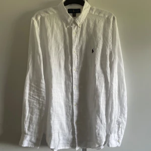 Linneskjorta  - Vit Ralph lauren linneskjorta. Den är i nyskick. Använd typ två gånger. Men kan inte ha den längre för den är för stor. Den är i storlek XL (18-20) för barn. Så den sitter typ som en xs/s men den är väldigt bred, där av säljer jag den. Nypris 1200kr