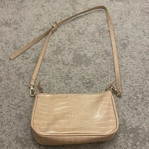 Kappahl väska beige - Denna väskan är jätte fin och beige den är använd ett par gånger fast i ganska bra skick bara att den är en fläck av läppglans i väskan men det går säkert bort annars är den helt som ny. 