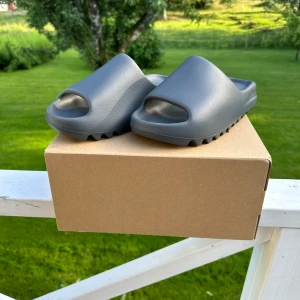 Yeezy Slide Slate Grey - Säljer ett par Yeezy Slide Slate Grey i storlek 42. Helt nya aldrig använda och original boxen finns kvar. Hör av dig för mer info eller frågor!  Kan gå ner lite i pris vid en snabb och smidig affär