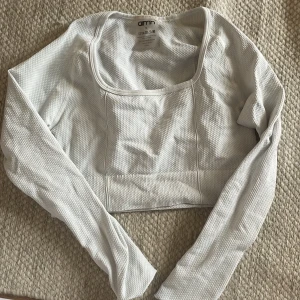 Vit långärmad topp från Aim'n - En vit långärmad topp från Aim'n. Toppen är tillverkad av 92% polyamid och 8% elastan, vilket gör den stretchig och bekväm. Den har en fyrkantig halsringning och är croppad i modellen. jättefin men tyvärr för liten och därför aldrig använd