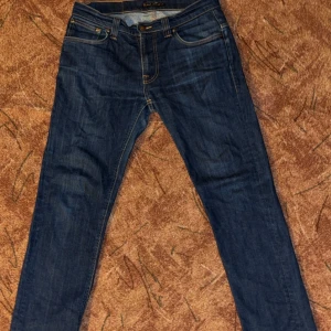 Nudie jeans thin finn -  Jeansen är i mycket gott skick. De var ursprungligen i storlek 32/32, men har krympt i tvätten och passar nu perfekt för någon som är cirka 170 cm lång. Tveka inte med att höra av dig vid frågor eller funderingar.