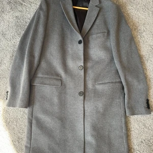 Rock - 1 år gammal grå  rock från H&M som aldrig har använts. Nypris 1200kr. Den är grymt snygg men passade inte mig så därför säljer jag den. Storlek 54. 