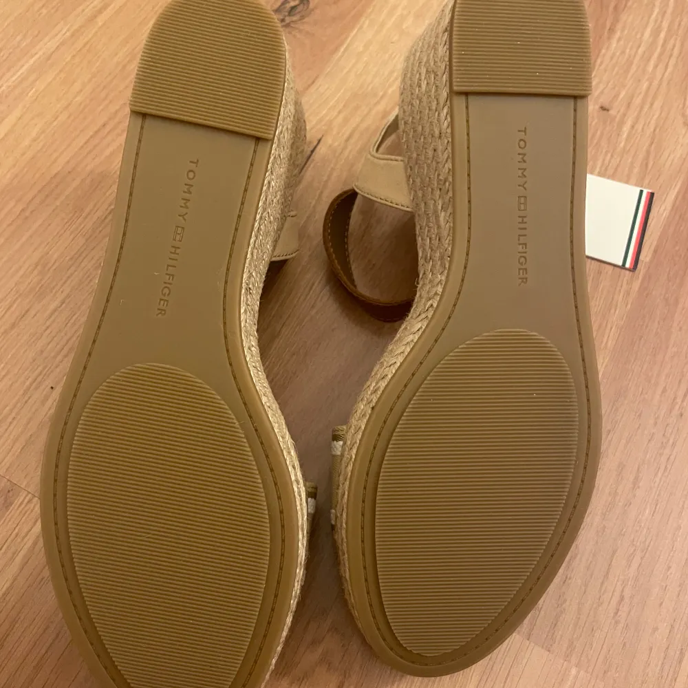 Helt nya & oanvända skor från Tommy Hilfiger i storlek 39. Köpta för 1200kr, modell: Webbing wedge sandal.  På högra skon saknas läderremmen för spännet (se bild 4). . Skor.