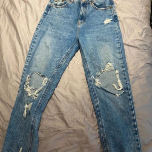 Blåa jeans med hål  - Mom jeans med hål vid knän. Luftiga och sköna. Kan kläs ner eller upp. 