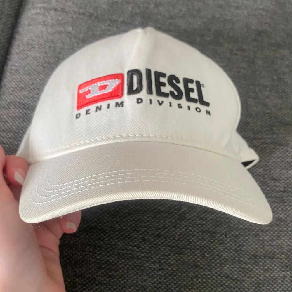 Säljer en vit äkta diesel keps med deras märke broderat på framsidan🤩Den är justerbar där bak så passar många storlekar!! Eftersom den är vit är den lite missfärgad (se bild 5), men annars i bra skick🙌🏻Nypris: 689kr. Billiga kläder➡️min profil😚. Accessoarer.