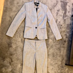 Grå kostym från Zara - Jättebra skick!  En elegant grå kostym bestående av en kavaj och byxor. Kavajen har en enkelknäppning med en knapp och är figursydd för en smickrande passform. Byxorna är raka och matchar kavajen i färg och material.