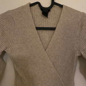OMLOTT TRÖJA - Snygg omlott urringad beige tröja. Stickad, när man har på sig tröjan sitter den som första bilden och håller sig på plats. Jättefin och bra skick. Köpte för 300kr från Lindex, säljer nu för 150.
