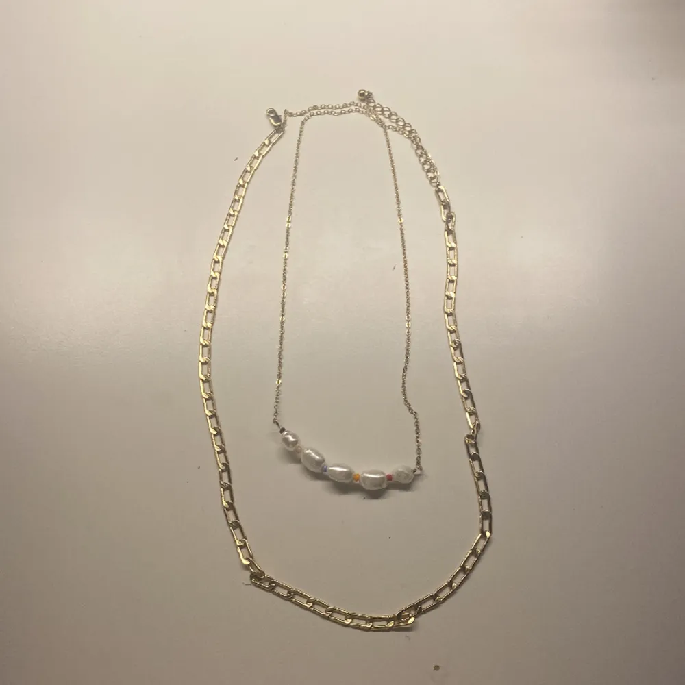 Det är en halsband som är två i en. Med pärla och det är guldiga.. Accessoarer.