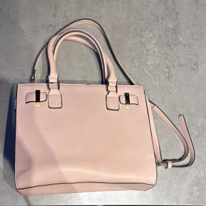 Väska  - Jättefin rosa väska som är helt oanvänd!! Den har justerbart band och flera fack för mer plats!!Mått: 31cm (längd) x 25cm (höjd) x 14cm (bredd)