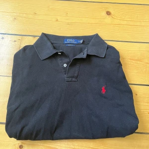 Ralph lauren pike - Svart Ralph lauren pike i storlek L (passar även M). Skicket är bra förutom att baksidan av tröjan är lite längre än framsidan. Nypris är ca 1200kr, vårt pris är 299kr