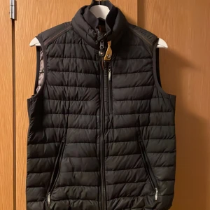 Parajumper Väst - Hej, säljer min väst då den blivit för liten. Skicket på västen är bra 9/10. Västen har en skada på den gula knappen (bild 4). Västen sitter kort på mig som är 180. 