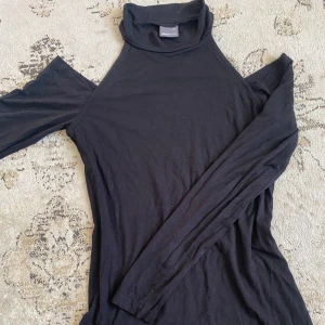 Tröja med öppna axlar gina tricot - Svart polotröja med öppna axlar. Använd 1-2 ggr, ser endast lufdig ut på bild fint skick annars. Pris:50kr storlek xs