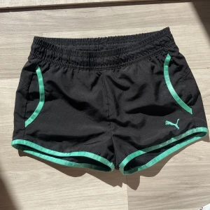 Shorts -  Super snygga svarta lågmidjade/midwaist shorts med turkosa detaljer från Puma som är perfekta att ha till träningen/sport nu till sommaren!⭐️ Man kan justera passformen runt midjan på insidan av shortsen med snören💗Endast använda 1 gång, Nyttskick!⭐️