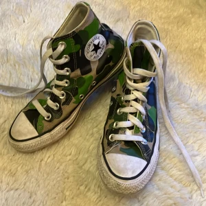Kamouflage-converse - Knappt använda converse. Tvättas såklart innan de skickas. Förutom små tvättbara jordfläckar ser de nästan helt nya ut. Värt att notera att ett namn står på insidan i ena skon samt lite konstig text på ena converse-loggan.  Pris går att diskutera!