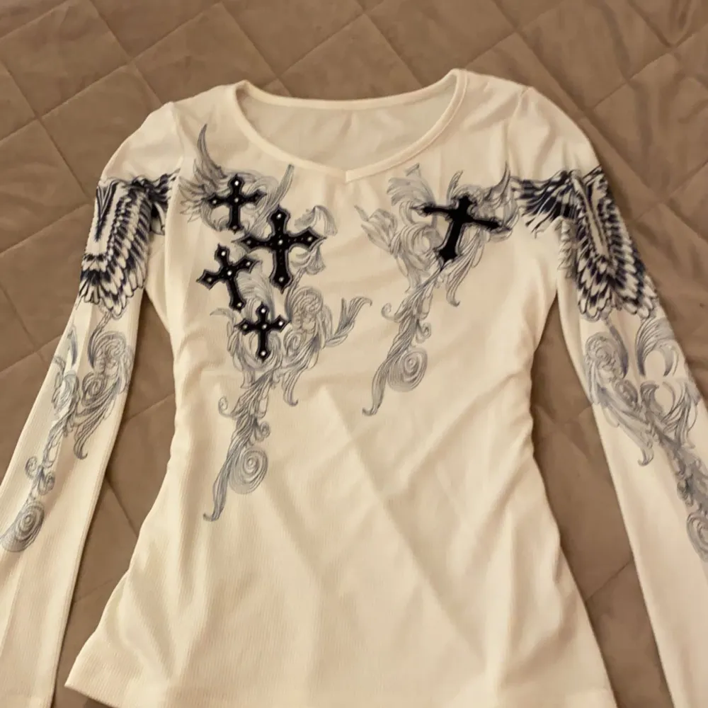 En svartvit supercool tröja med kors och vingar på!  I storlek s med en tajt passform! ❤️ Obs! Första bilden lånad från Pinterest men det är samma tröja!!! . Toppar.